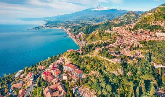 An aerial view of Taormina with Mount Etna in the background in Sicily, Italy